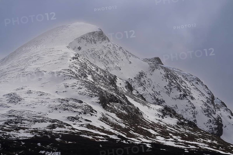 Snow-capped mountain peak with snowwoods and rocky ridge, fog at the summit, Andes, Tierra del Fuego, Argentina