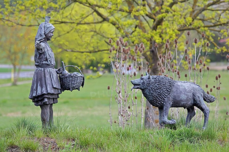 Little Red Riding Hood sculpture by Ewald Rumpf 2010, modern art, bronze sculpture, girl with wicker basket and traditional costume, fairytale figure and the bad wolf, wolf figure, Deutsche Märchenstraße, Remsfeld, Knüllwald, Knüllgebirge, Hesse, Germany