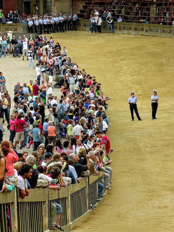 Il Palio di Siena, historical horse race, audience on the square behind barriers, policemen guarding the finished racecourse in front of the race, Piazza del Campo, historic centre, Siena, Tuscany, Italy