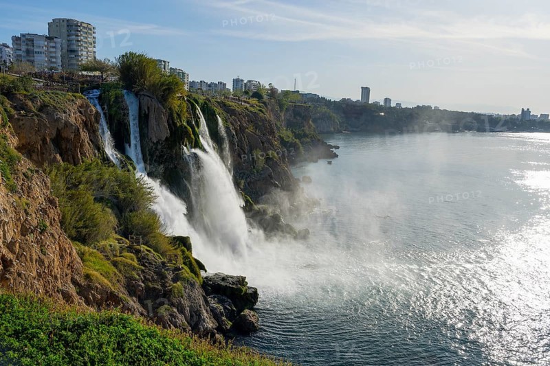 Extensive coastal view with waterfall, urban environment and calm sea, Lower Düden Waterfall, Düden River, Antalya, Turkey