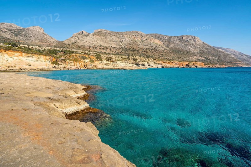 Breathtaking view of Greece's coastline featuring vibrant turquoise waters and rocky shores under a clear blue sky, capturing the serene beauty of Mediterranean landscapes