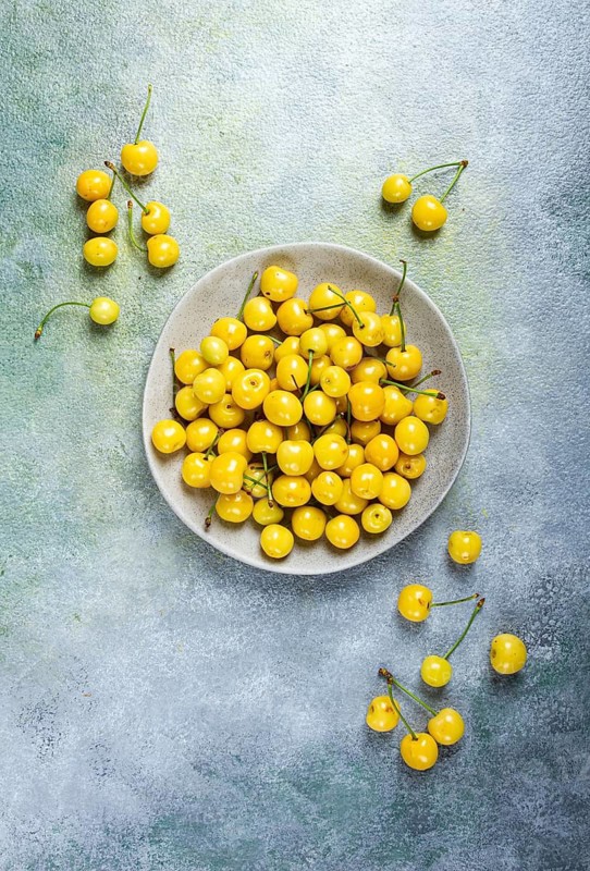 Yellow cherry, cherry berry, scattered on a plate, top view, no people