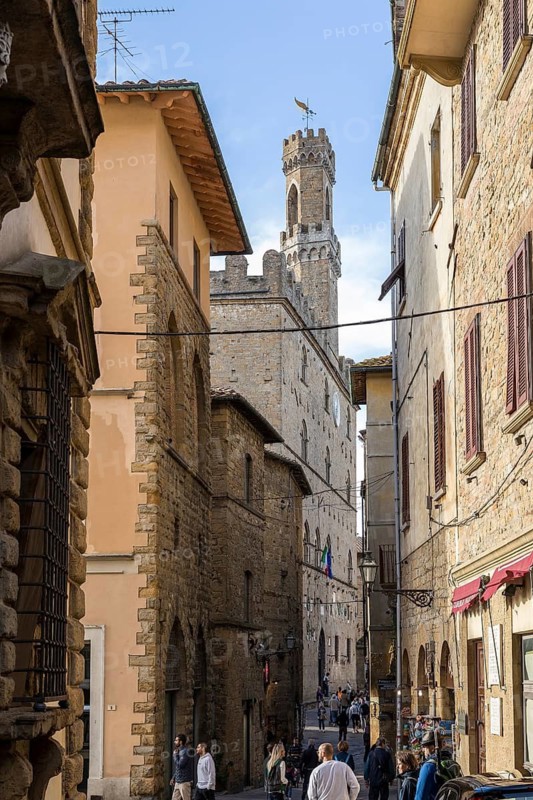 Visual axis through a narrow alley to the Palazzo dei Priori on the main square of Volterra, province of Pisa, Tuscany, Italy