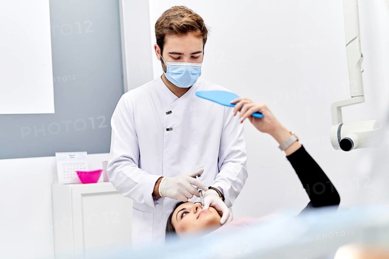 A doctor, wearing white sterile gloves, carefully administers a hyaluronic acid injection to a patient in a modern medical office, emphasizing precision and care