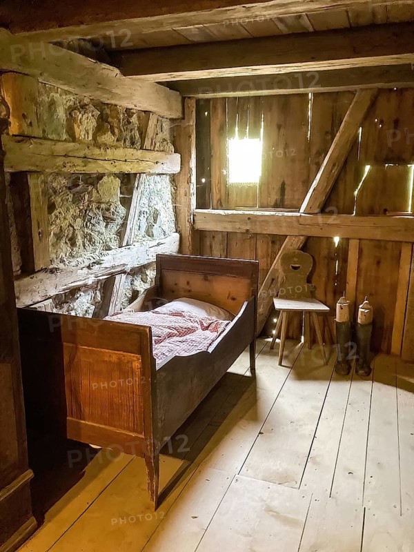 Historic bedroom with single bed for one person on the right chair made of wood and pair of boots with boot stretchers in old rebuilt restored small farmhouse weaver's house half-timbered house in open-air museum Neuhausen, Neuhausen ob Eck, district Tuttlingen, Baden-Württemberg, Germany