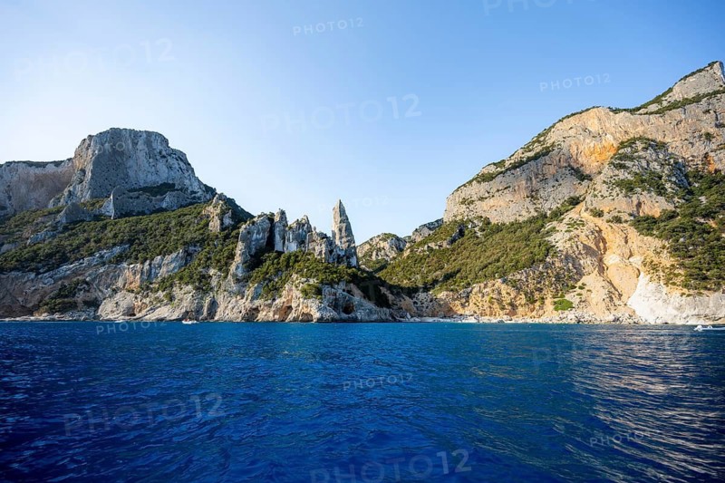 Picturesque rocky coast, cliffs with caves in the morning light, L'Aguglia rock peak, blue sea and Cala Goloritzé beach, Golfo di Orosei, Baunei, Sardinia, Italy