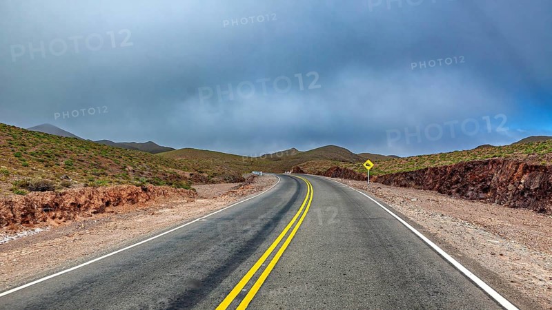 Empty road snakes through a dry, hilly landscape, roads through the Quebrada de Cafayate countryside near Salta in Argentina