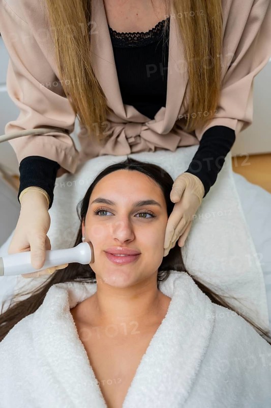 Young woman receiving a radiofrequency facial treatment from an esthetician, enhancing skin rejuvenation and beauty at a modern aesthetic clinic or spa center