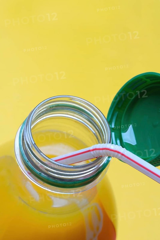 Orange juice in plastic bottle with cap and straw