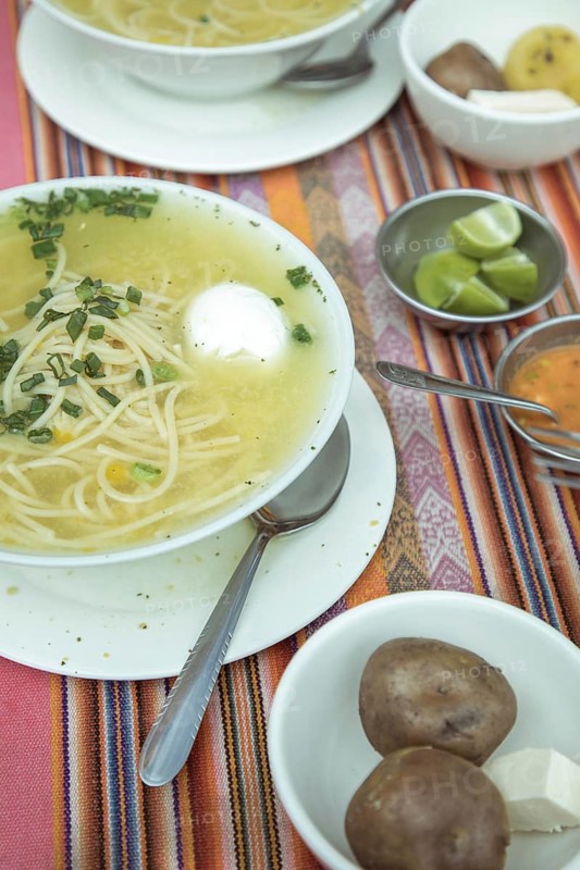 Sopa de gallina with egg, chicken soup, traditional dish in the Andean highlands of Peru, with lime, boiled potatoes, fresh cheese and ají, La Oroya, Peru