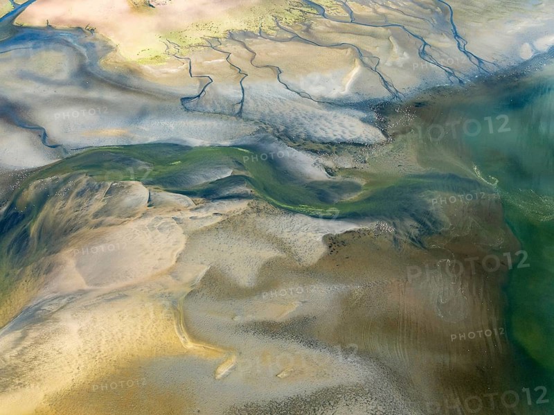 Streams and marshes at low tide in the coastal wetlands of the Walvis Bay lagoon. In the distance Greater Flamingos (Phoenicopterus ruber). Aerial view. Drone shot. Walvis Bay, Namibia
