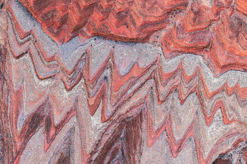 This aerial image captures the intricate, colorful patterns of a rugged canyon landscape near the San Juan River in Utah, highlighting the area's dramatic natural beauty