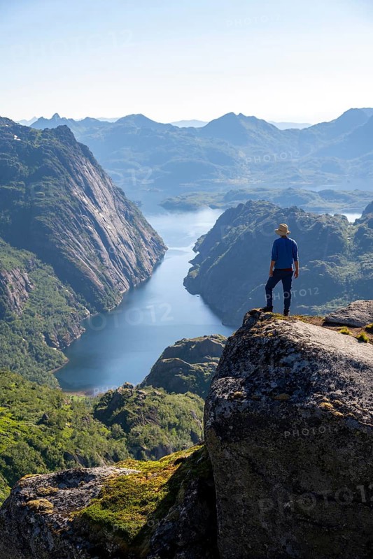 Mountaineer, young man in front of mountain landscape, fjord Trollfjord and mountains, hike to Trollfjord Hytta, at Trollfjord and Raftsund, Lofoten, Nordland, Norway