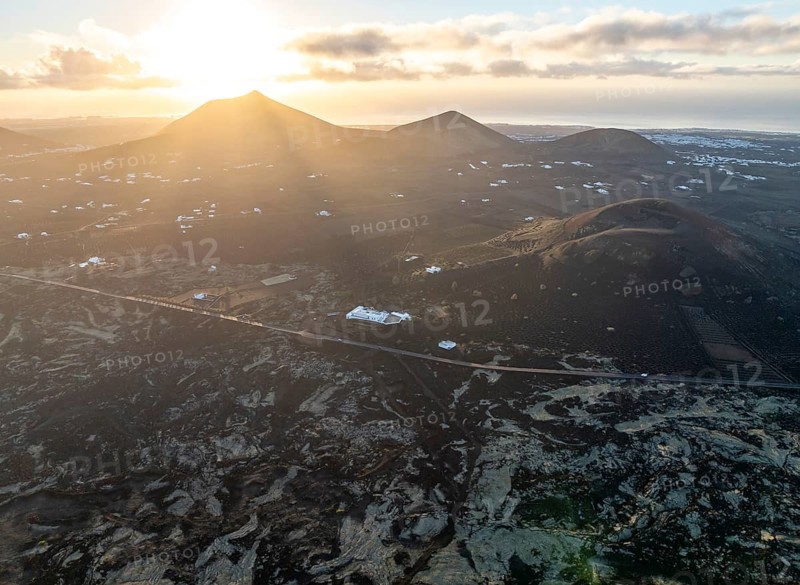 White houses in picturesque volcanic landscape with volcanic craters and lava fields in morning light, aerial view, Lanzarote, Canary Islands, Spain