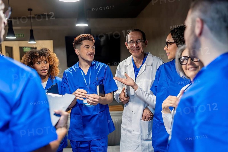 Healthcare team of doctors and nurses collaborating, smiling, and discussing patient care in a modern hospital setting, fostering teamwork and professional development