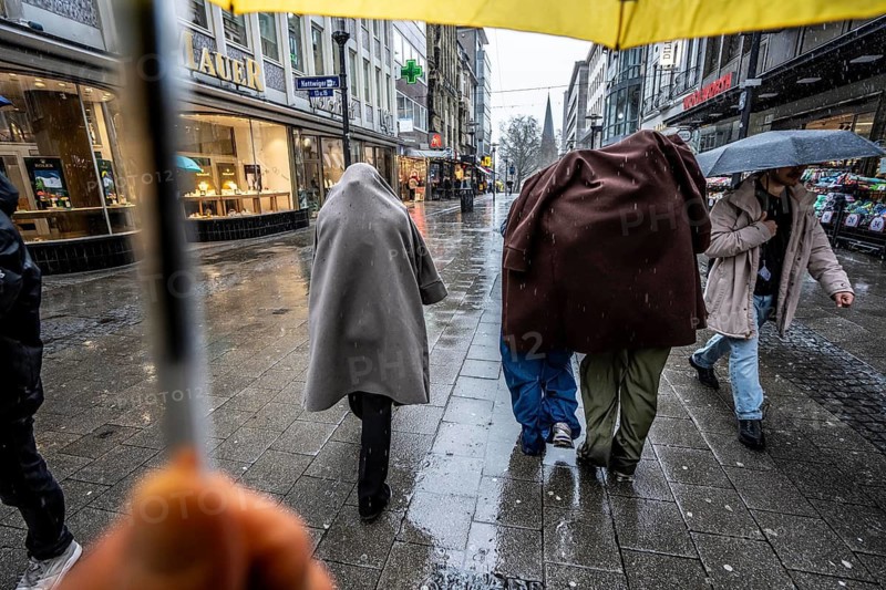 Passers-by in a pedestrian zone, Kettwiger Straße, young woman in rainy weather, without an umbrella, protecting themselves from the rain with coats and jackets, city center, Essen, North Rhine-Westphalia, Germany