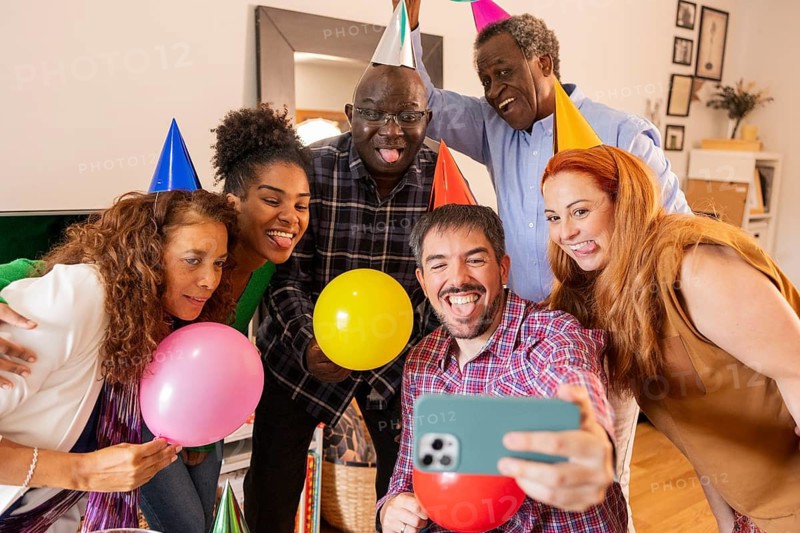 A joyful group of friends taking a selfie during a birthday party, wearing colorful hats and holding balloons, capturing the essence of celebration and happiness