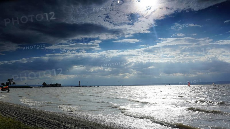 Waves roll across the beach as clouds move across the sunny sky, Lake Neusiedl, Austria