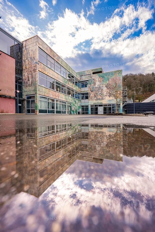 Modern building reflected in a water surface under a dramatic sky, Nagold, Calw district, Germany