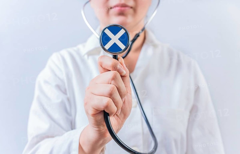 Female doctor holding stethoscope with Scottish flag. National health system of Scotland
