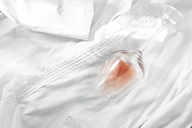 Glass, with pink wine, spilled on a white shirt, close-up, selective focus, no people, concept, top view
