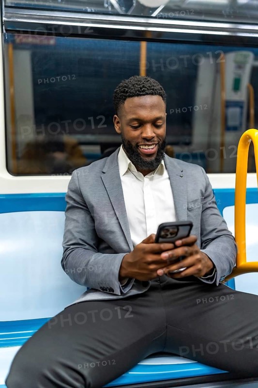 Smiling businessman using a mobile phone app while commuting on a subway train, enjoying the convenience of modern technology and communication