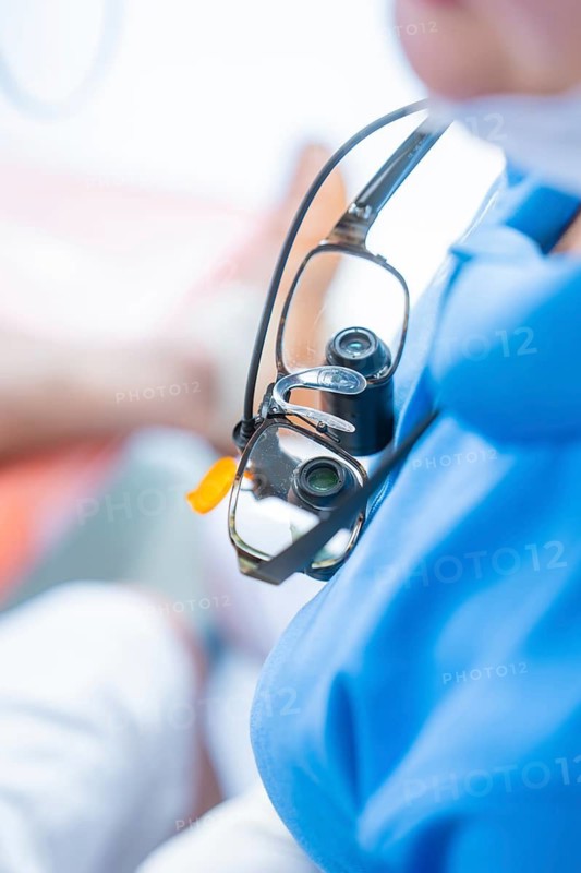 Close-up of medical magnifying glasses worn over a blue gown, dental practice, Germany