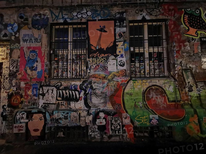 Colourful street art covers a wall with barred windows in an urban scene, Berlin