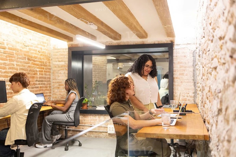 A diverse group of coworkers engaging in a collaborative workspace with laptops. The image highlights the inclusivity and multicultural environment of a modern office setting