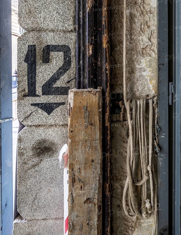 An industrial-themed image showing peeling paint on an old wall, rusty pipes, and coiled ropes. A visible number 12 enhances the gritty, work-in-progress look