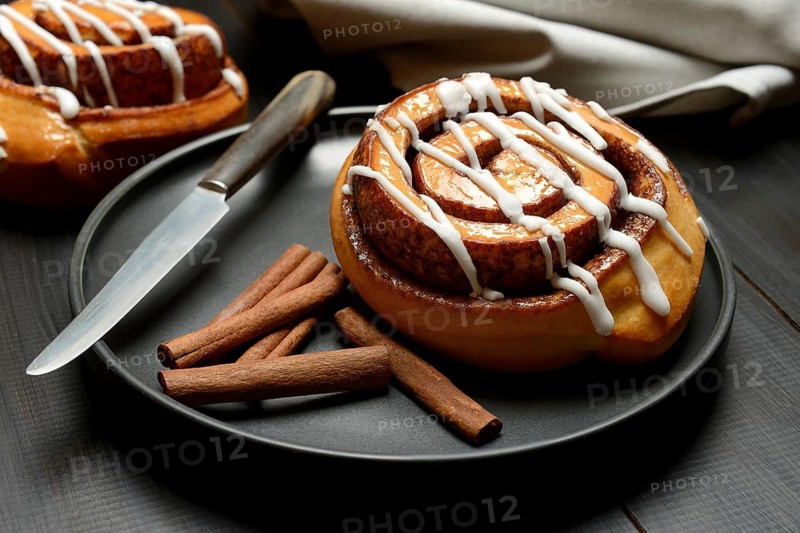 Cinnamon roll on plate and cinnamon sticks