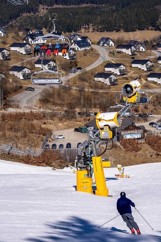 Winter sports area in the Sauerland, Winterberg ski lift carousel, artificial snow slopes, artificial snow from over 360 snow guns, Poppenberg ski area, background holiday homes at Landal Ferienpark Winterberg, 12 of 24 lifts are in operation in mid-March, the rest of the landscape is snow-free, North Rhine-Westphalia, Germany