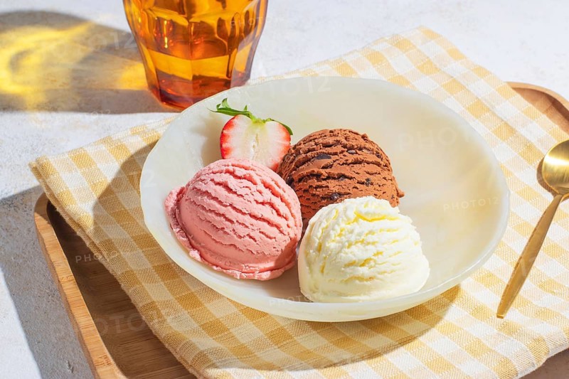 Delicious ice cream trio on a wooden tray with golden spoon, captured from a slightly high angle with bright natural lighting