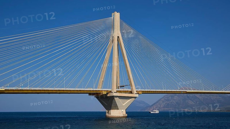 Suspension bridge with concrete pillars and a passing ship, Rio-Antirrio cable car bridge, Patras, Peloponnese, Greece