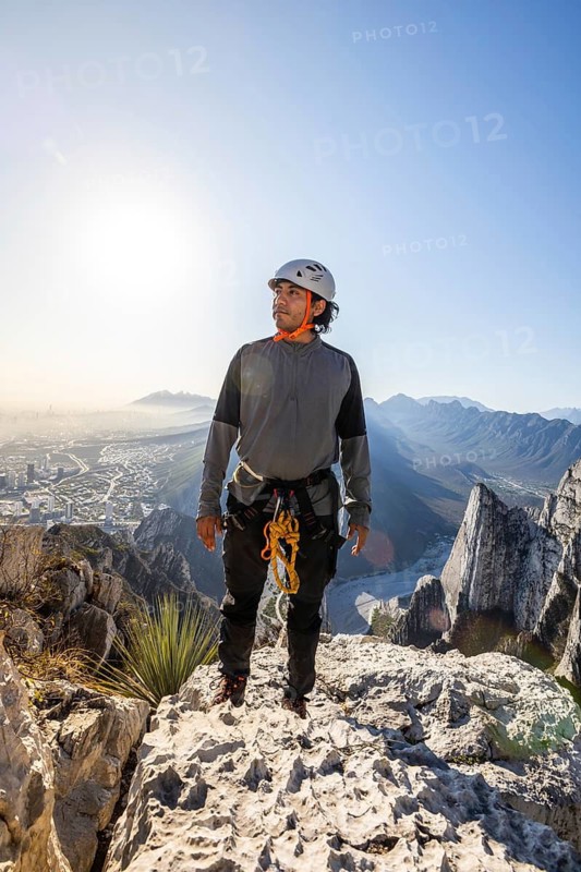 A man enjoys a moment of rest after practicing mountaineering and rappelling in the scenic Eagle's Nest, Monterrey, Mexico, surrounded by breathtaking cliffs and city views