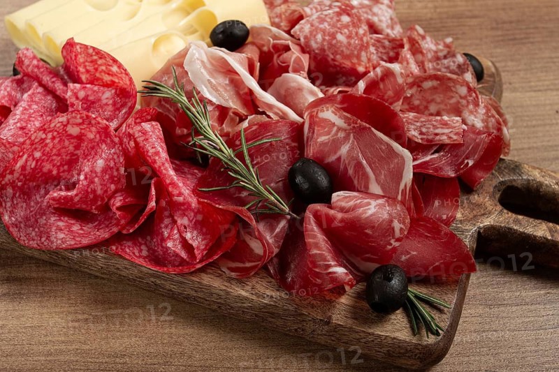 Assorted meat, appetizer, prosciutto, salami and ham, with maasdam cheese and olives, on a wooden board, breakfast, top view, close-up, no people