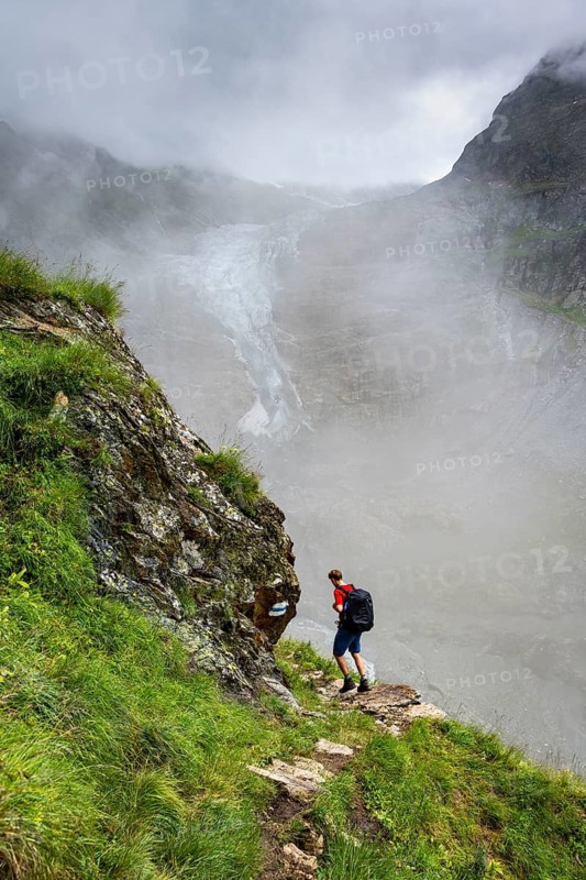 Mountaineers on a hiking trail, cloudy mountain landscape with Lower Arctic Sea glacier, Bernese Alps, Bernese Oberland, Switzerland