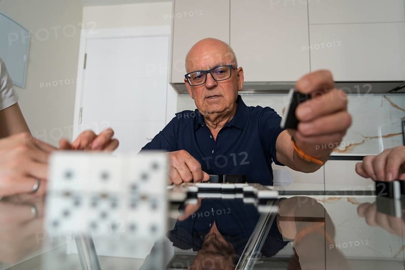 A family engages in a lively game of dominoes, fostering connection and enjoyment while gathered around the kitchen table, reflecting togetherness and joy