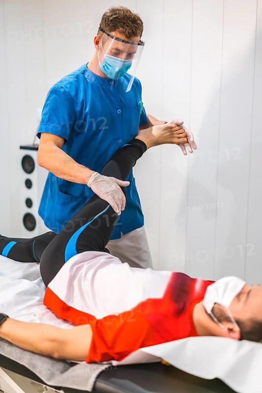 A physiotherapist with mask working with a patient. Physiotherapy with protective measures for the Coronavirus pandemic, COVID-19. Osteopathy, therapeutic chiromassage