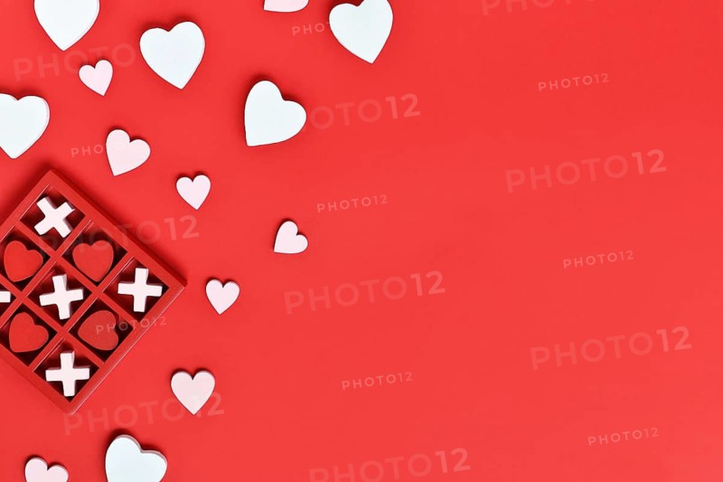 Valentine-themed heart game with red hearts and white Xs in a red box on a red background with copy space