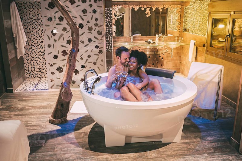 Happy interracial couple relaxed in the jacuzzi enjoying their self and drinking wine