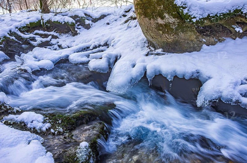 Small watercourse in winter with ice floes and mossy stones, Brühlbach below Urach Waterfall, Bad Urach, Swabian Alb, Baden-Württemberg, Germany