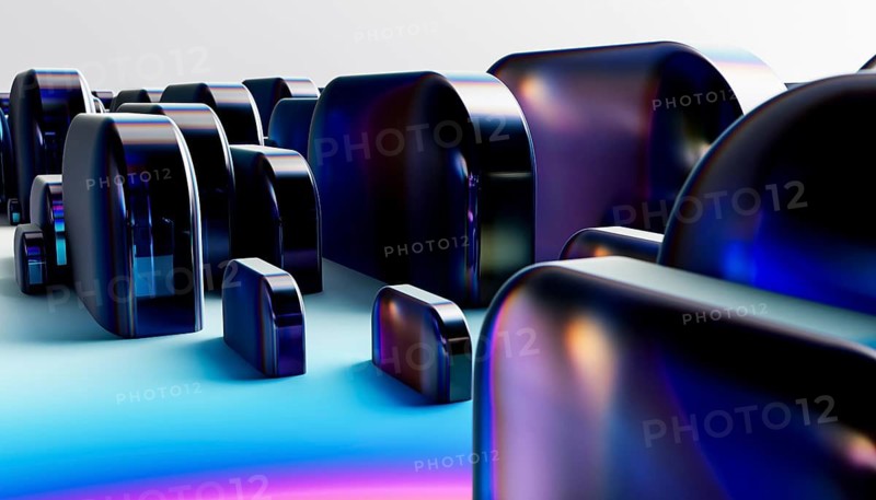 Abstract image featuring glossy, futuristic shapes in varying sizes. The objects reflect light in vibrant hues, creating a dynamic and modern visual effect