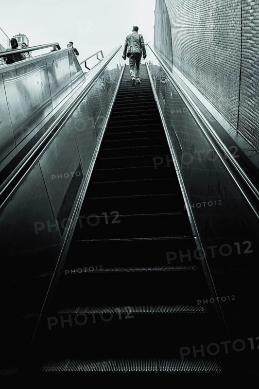 A man climbs a long, modern escalator in monochrome colours, Schlossplatz, Stuttgart, Germany