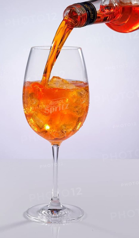 Aperol is poured into an Aperol spritz glass on ice cube cubes, studio shot