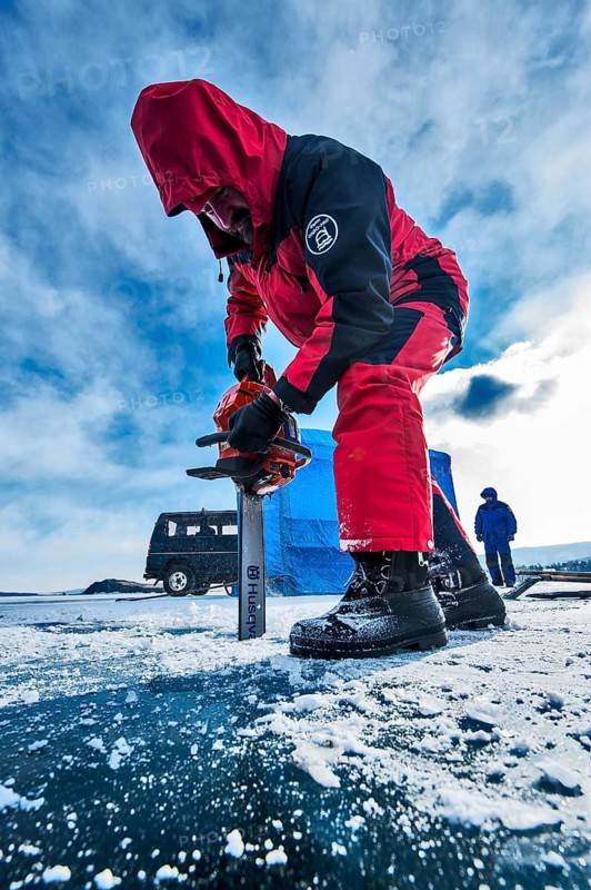 Digging a hole in ice for scuba divers with a chainsaw, Lake Baikal, Olkhon Island, Pribaikalsky National Park, Irkutsk Province, Siberia, Russia