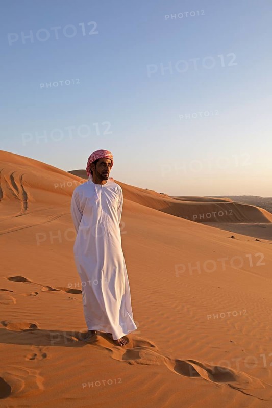 Bedouin man in white dishdasha on a sand dune, Wahiba Sands or Rimal Al Wahiba or Sharqiyya Sands desert, Janub ash-Sharqiyya region, Oman
