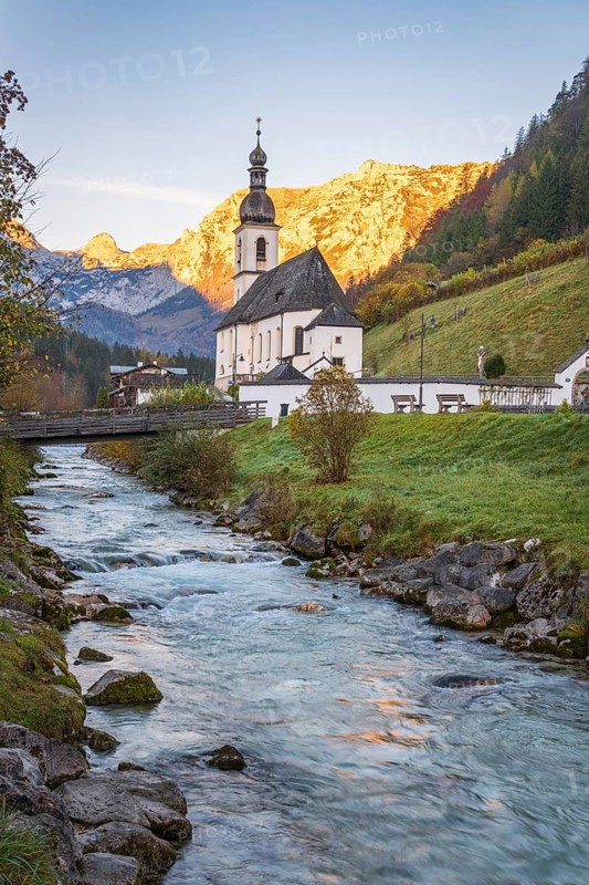 St Sebastian Parish Church in Ramsau, nestled by a serene stream with the Bavarian Alps in the backdrop, showcases the tranquil beauty of an idyllic alpine setting at sunrise