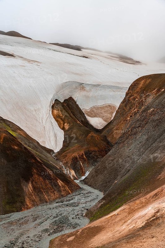 Steaming stream between colourful rhyolite mountains and snowfields, Hveradalir geothermal area, Kerlingarfjöll, Icelandic Highlands, Iceland