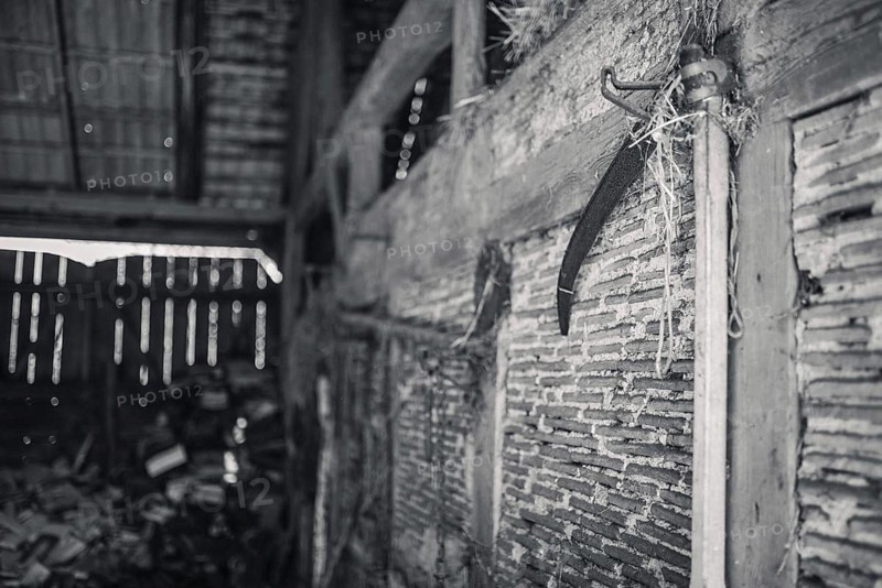 A scythe hanging on the wall of an old barn in Poland